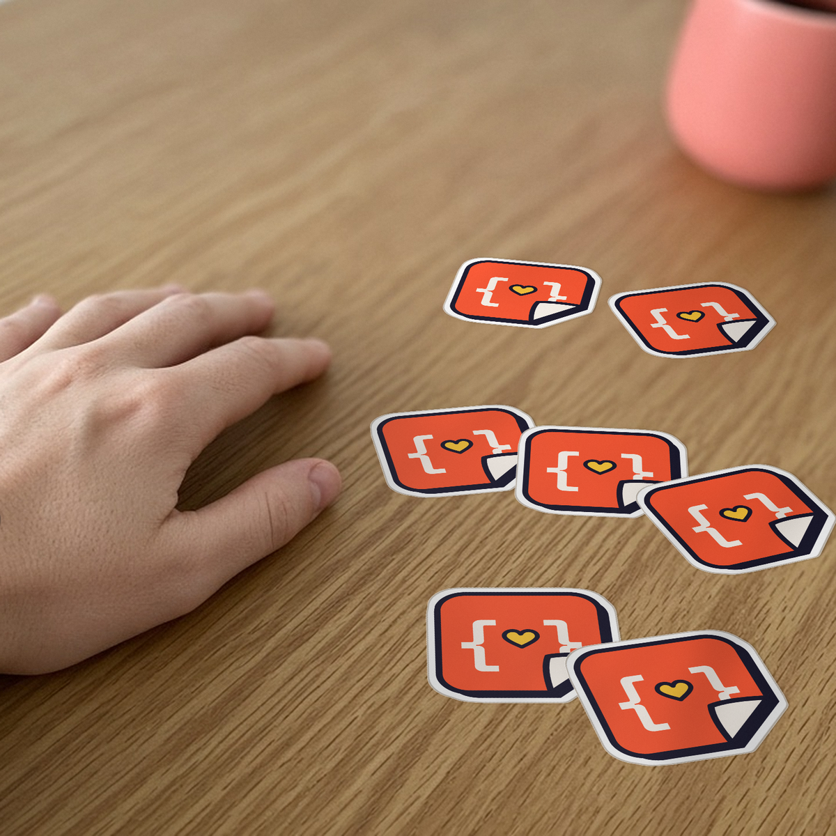 Custom Die-Cut Stickers: seven matching die-cut vinyl stickers with the StickerCon logo on a wooden desk beside a hand.