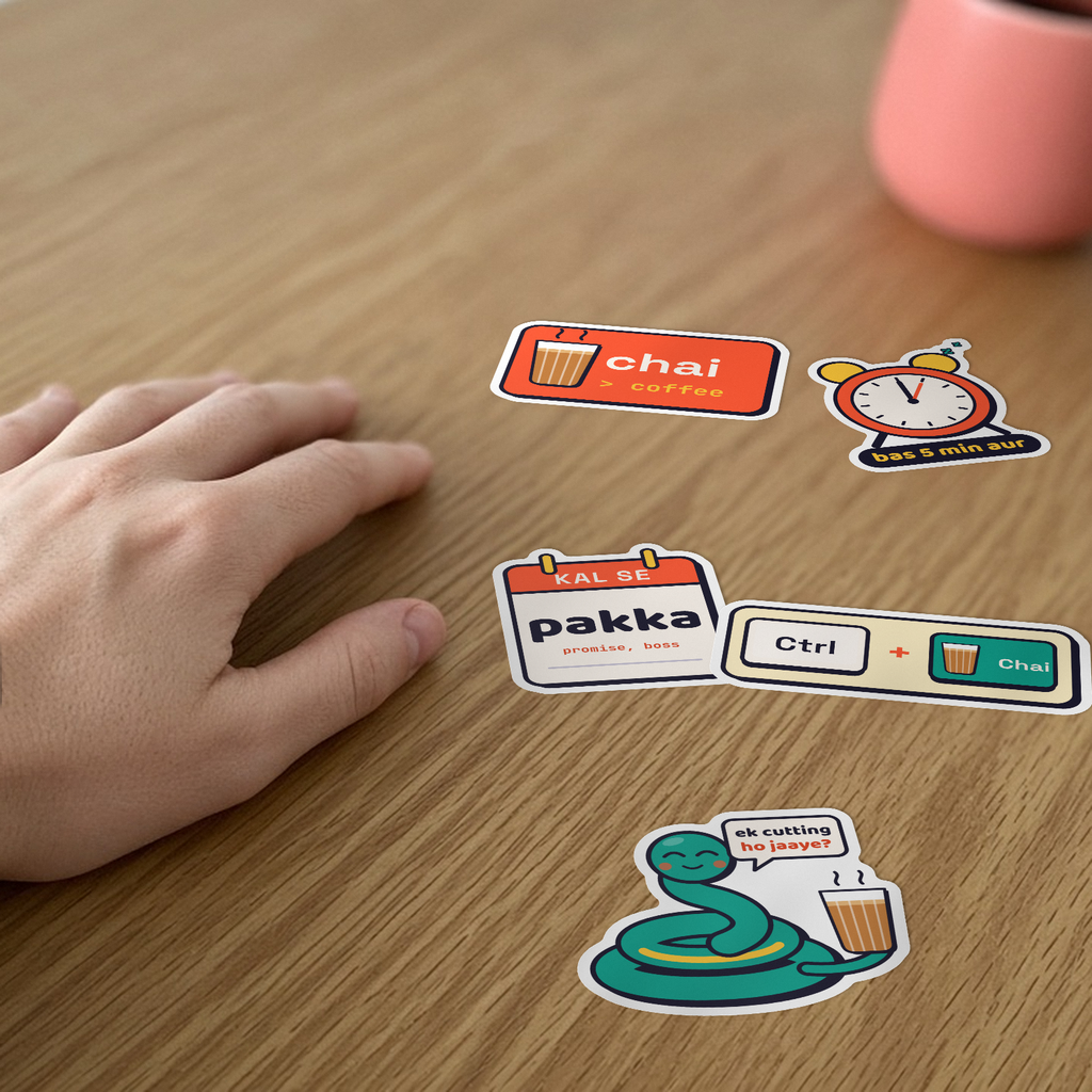 Desi Dev Sticker Pack: five stickers, including Chai > Coffee, Bas 5 min aur and Ctrl + Chai, on a desk beside a hand.