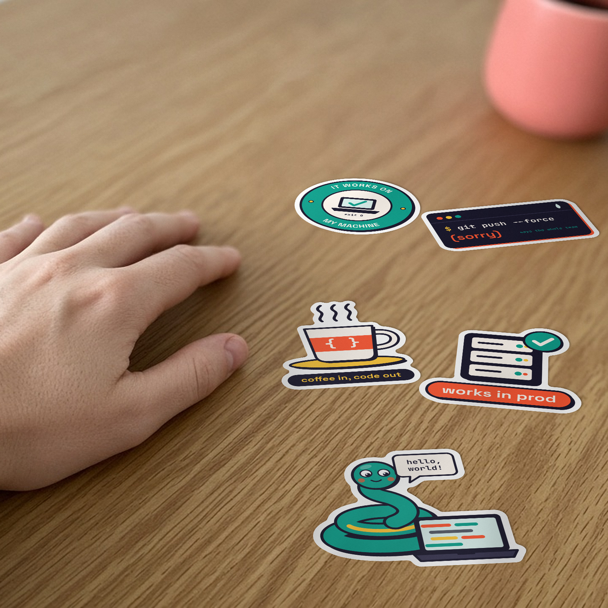 Dev Life Sticker Pack: five dev stickers, including git push --force (sorry) and Works in prod, on a desk beside a hand.