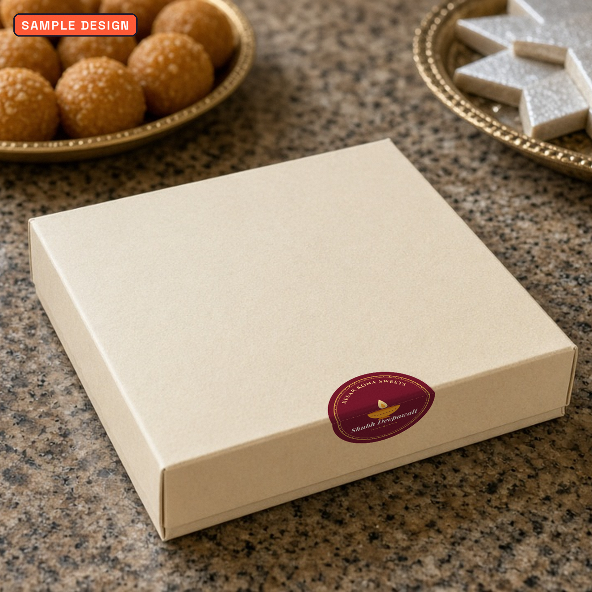 Diwali box seal sticker, 50 mm round diya design for Kesar Kona Sweets, folded over the edge of a cream sweet box with laddoos and kaju katli behind, sample design for a made-up sweet shop