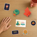 Diwali Desk Set on a desk beside a hand: Diwali Pip with a diya, phone stand, Shubh Deepavali desk card and festive stickers