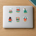 Holiday Mode Sticker Pack: six die-cut vinyl stickers on a laptop lid, including Out of Office snow globe, Code Freeze Pip, Kulhad Cat, Senior Reviewer, Window Seat and Locked In