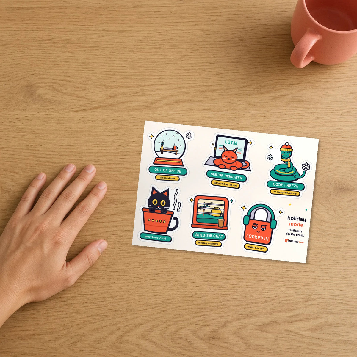 Holiday Mode Sticker Pack 5 x 7 inch kiss-cut sheet on a desk beside a hand for scale