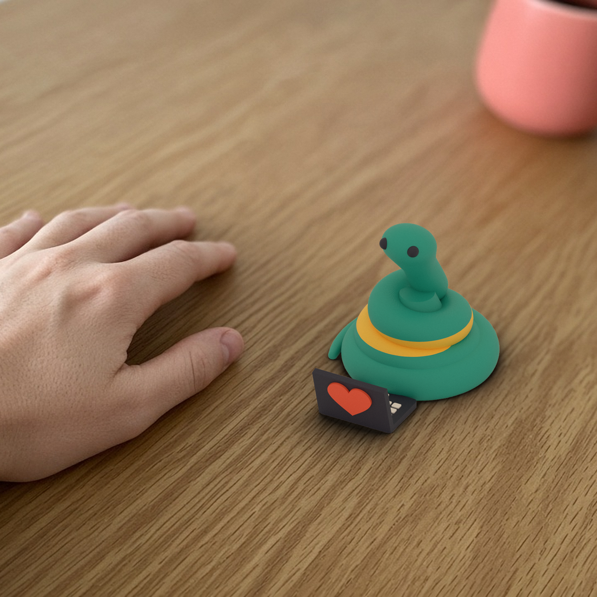 Laptop Pip: 3D printed teal snake with its tiny heart laptop beside a hand for scale.