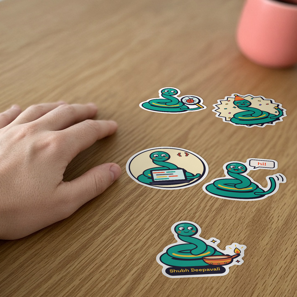 Pip Sticker Pack: five Pip the snake stickers, including Pip coding and Pip lighting a diya, on a desk beside a hand.