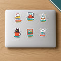 Recess Club Sticker Pack: six stickers on a laptop lid including Tiffin Time, Big Dreams paper rocket, Kulhad Cat, Senior Reviewer, Window Seat and BOOlean Ghost