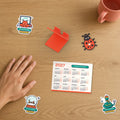Secret Santa Desk Set: 2027 calendar, phone stand, bug keychain and Holiday Mode stickers beside a hand