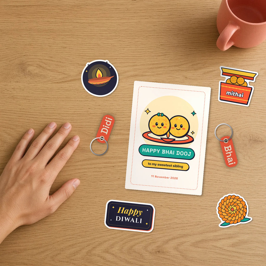 Bhai Dooj Sibling Set on a desk beside a hand: gift card, two name keychains reading Didi and Bhai, and festive stickers