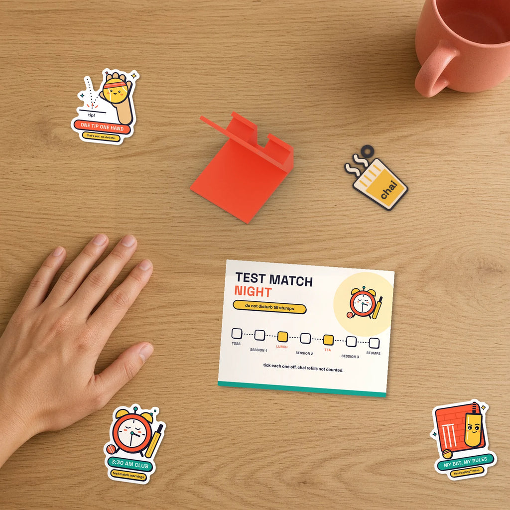 Test Match Night Set beside a hand: folding Test Match Night session tracker card, phone stand, chai keychain and Gully Rules stickers